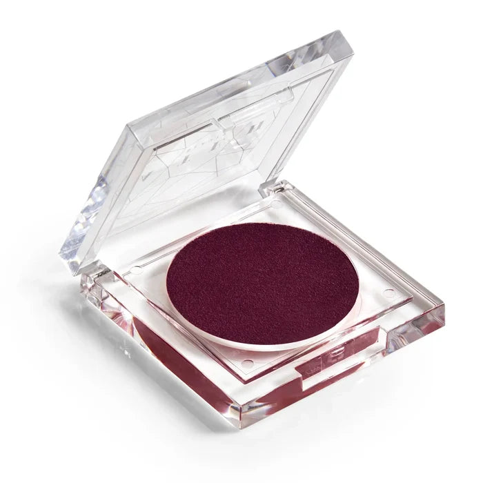 A pan of rich, juicy plum-colored blush makeup with a clear lid.