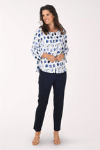 Woman wearing a patterned blouse and black pants on a white background