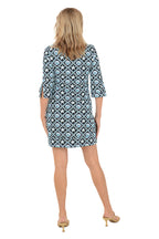 Woman wearing a patterned dress on a white background. Back shot.