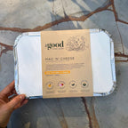 Mac 'n' Cheese packaging from the Good Farm Shop held by a hand on a stone surface.