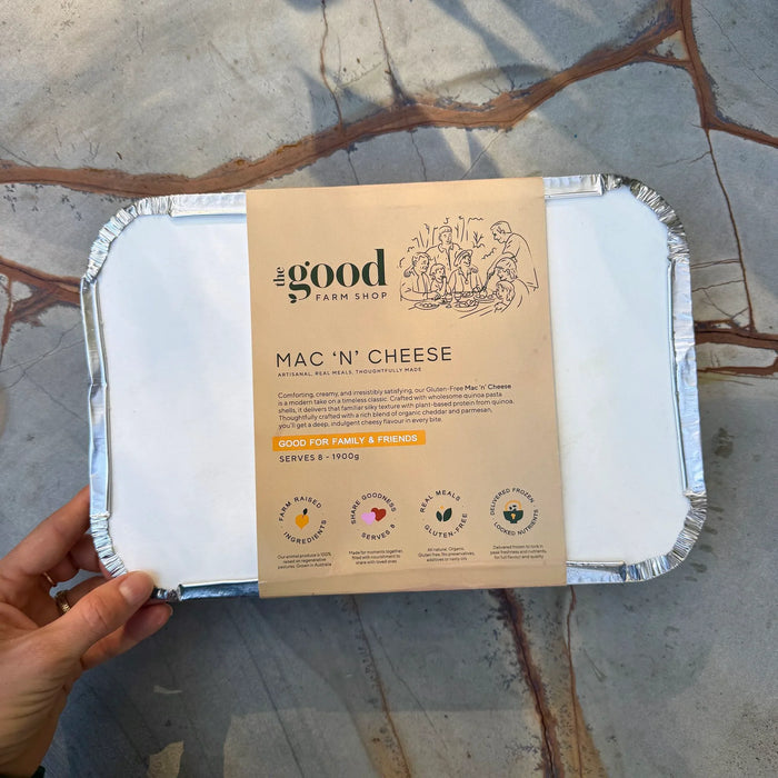 Mac 'n' Cheese packaging from the Good Farm Shop held by a hand on a stone surface.