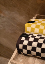 Black and yellow checkered towels stacked on a stone tray.