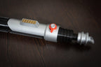 Ezra Bridger second lightsaber hilt cosplay prop in silver and black with red button detail on wooden surface
