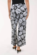 Black and white butterfly-patterned pants worn by a person on a white background