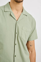 Flint Collared Button Shirt with Short Sleeves and a Chest Pocket in Sage Colorway. Front View Shown on Model.