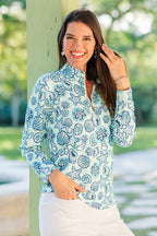 Woman wearing a blue floral patterned shirt with a blurred green outdoor background