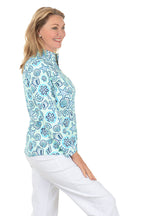 Woman wearing a blue floral patterned blouse on a white background. Side shot.
