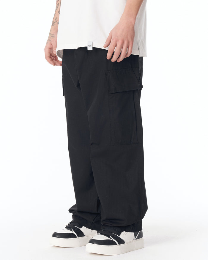 Martin Valen men's black cargo pants mid-body view showing side cargo pockets and white sleeveless top