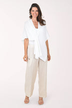 Woman wearing a white top and beige pants on a white background