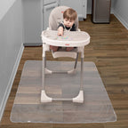 A baby sits in a high chair with snacks on the tray, while the Nuby US No-Mess Mealtime Mat serves as an easy-to-clean floor protector on the wooden kitchen floor.