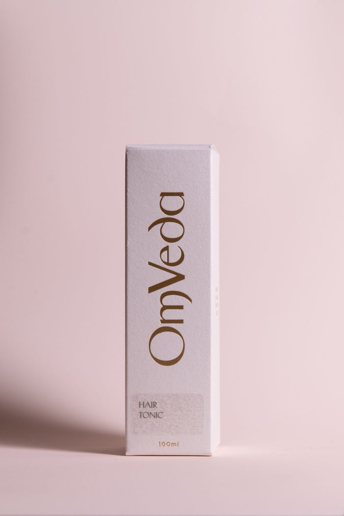 OmVeda hair tonic box, white packaging with brown logo text