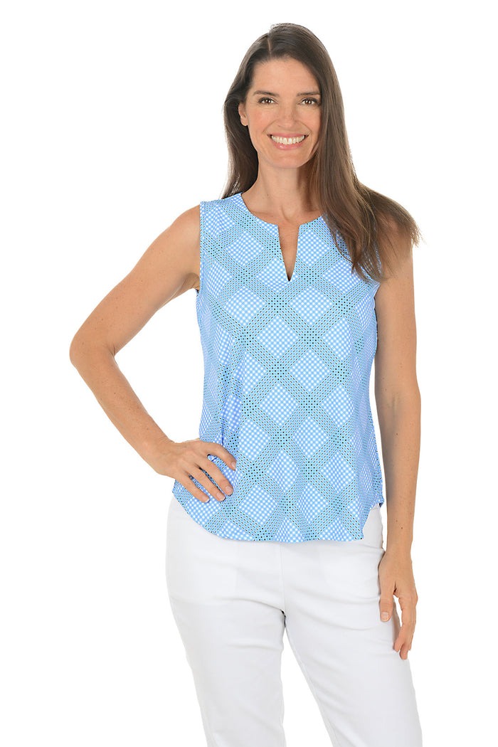 Woman wearing a light blue checkered sleeveless top and white pants on a white background. Side shot