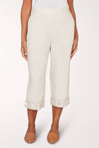 Person wearing white pants with lace cuffs on a white background
