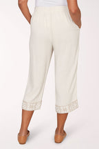 Person wearing white pants with lace cuffs on a white background