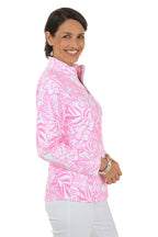 Woman wearing a pink floral patterned shirt with a white background. Side shot.