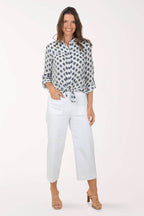 Woman wearing a patterned blouse and white pants on a white background