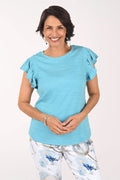 Woman wearing a light blue ruffled blouse with floral pants on a white background