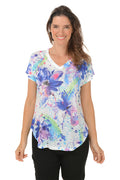 A woman wearing a multi colored floral short sleeve top.