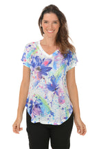 A woman wearing a multi colored floral short sleeve top.