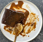 Half eaten slice of sticky date pudding with caramel sauce