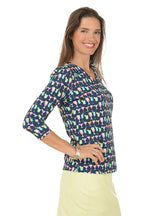Woman wearing a colorful cocktail patterned top and yellow skirt on a white background. Side shot.