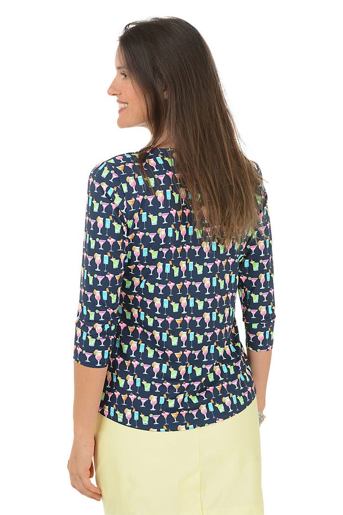 Woman wearing a colorful cocktail patterned top and yellow skirt on a white background. Back shot.