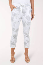 Person wearing white tie-dye pants on a light pink background
